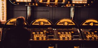 Ein Mann sitzt in dunkler Umgebung an einem Spielautomaten