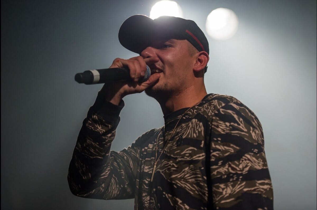 Capital Bra mit Mikrofon bei einem Konzert.