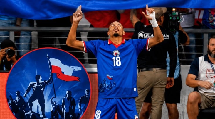 Haiti Nationalspieler ehren Polen mit Fahne auf dem Trikot.