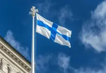 Uusi rahapelilaki kiristää pelaajansuojaa – mitä tämä tarkoittaa sinulle? uusi rahapelilaki ja pelaajansuoja - taustalla eduskuntatalo ja suomen lippu