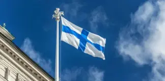 Uusi rahapelilaki kiristää pelaajansuojaa – mitä tämä tarkoittaa sinulle? uusi rahapelilaki ja pelaajansuoja - taustalla eduskuntatalo ja suomen lippu