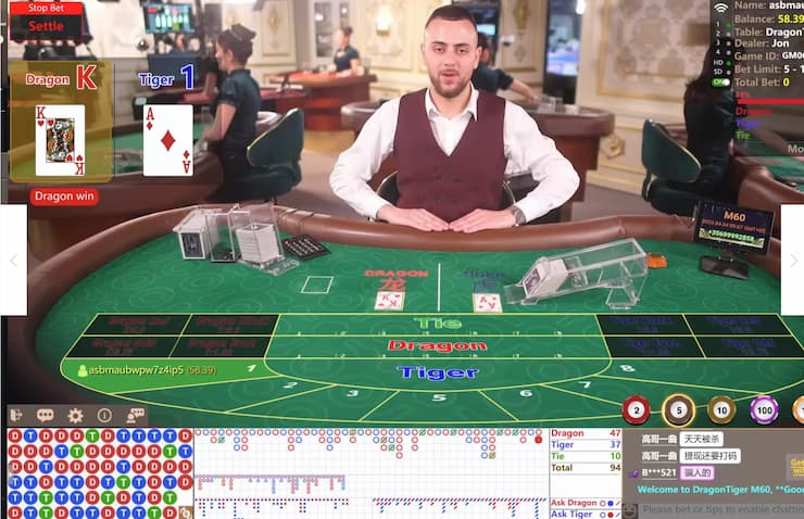 남성 딜러가 손을 가지런히 모으고 드래곤 타이거를 실시간으로 플레이중이다. 뒤에는 다른 딜러가 딜링중인 모습을 확인할 수 있다.