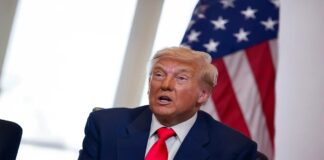 도날드 트럼프가 미국 국기 앞에 앉아 있는 모습