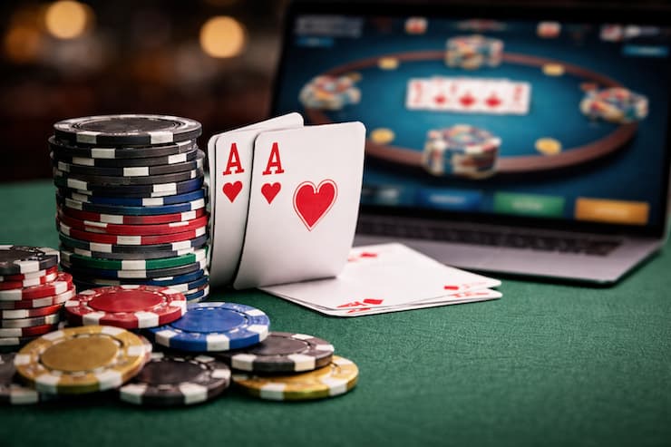 노트북 화면에 온라인 포커 테이블이 표시된 가운데, 테이블 위에 쌓인 포커 칩과 에이스 카드 두 장이 놓여 있는 온라인 포커 이미지