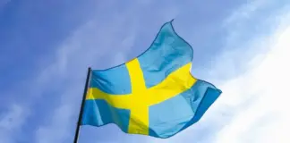 Sveriges flagga vajar mot en blå himmel.
