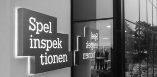 Skylt med texten Spelinspektionen utanför en byggnad, speglas i fönsterglas med personer synliga inomhus.