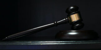 Domarklubba i trä ligger på ett bord mot mörk bakgrund.