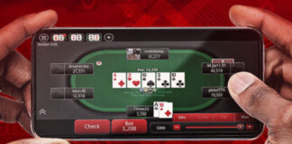 Två händer håller en mobil med ett pokerbord på skärmen och flera spelare runt bordet.