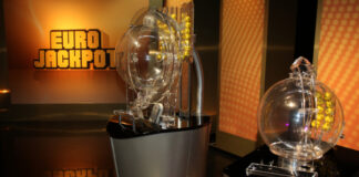 Två lottodragningmaskiner för Eurojackpot visas i en studio med bollar och logotyp i bakgrunden.