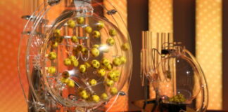 Lottobollar blandas i en genomskinlig maskin under dragning, med gul bakgrund och ljusa ljuspunkter.