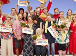 Grupp glada vinnare firar med blommor och stora checkar från Postkodlotteriet.