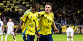 Två svenska fotbollsspelare firar mål i landslagets gula tröjor under en match på fullsatt arena.