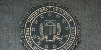FBI:s emblem i metall med texten Department of Justice Federal Bureau of Investigation på vägg.