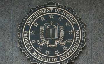 FBI:s emblem i metall med texten Department of Justice Federal Bureau of Investigation på vägg.