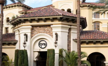 Elegant byggnad med tegeltak, palmträd och GVR-logotyp vid entrén till ett kasinohotell.