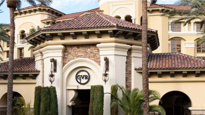 populärt-pokerrum-öppnar-igen Elegant byggnad med tegeltak, palmträd och GVR-logotyp vid entrén till ett kasinohotell.