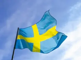 Svenska flaggan som vajar mot en klar blå himmel.