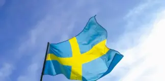 Svenska flaggan som vajar mot en klar blå himmel.