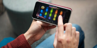 Person spelar en färgglad slot på mobiltelefon i ett avslappnad hemmamiljö.