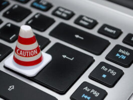 Litet varningskon med texten Caution placerat på tangenterna på ett dator­tangentbord