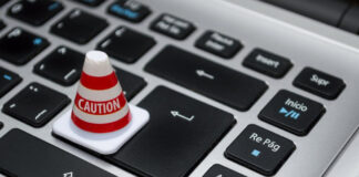 Litet varningskon med texten Caution placerat på tangenterna på ett dator­tangentbord