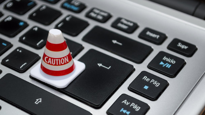 mga-varnar-för-falska-casinon Litet varningskon med texten Caution placerat på tangenterna på ett datortangentbord