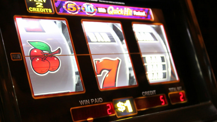 ny-casinolag-från-spelinspektionen Närbild på en spelautomat med körsbär och sjua på hjulen samt belyst display.