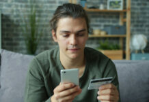 Ökning av unga med spelproblem i Sverige Ung man sitter i soffa och håller mobil och kreditkort när han gör ett köp online.