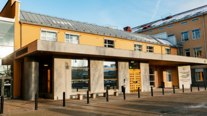 En gul byggnad vid en domstol/tingsrätt med entré och svart stolpar framför.