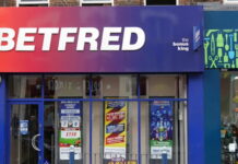 Betfred-butik med röd-blå skylt och reklam i fönstren på en brittisk gata.