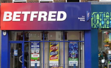 Betfred-butik med röd-blå skylt och reklam i fönstren på en brittisk gata.