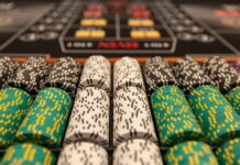 Närbild av staplade casinonmarker i olika färger på ett spelbord.