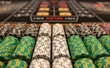 Närbild av staplade casinonmarker i olika färger på ett spelbord.