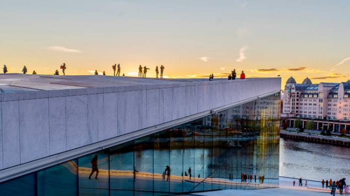 norsk-tipping-inleder-revision Oslo Operahus vid solnedgången med människor som promenerar på taket