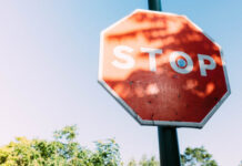 Spelinspektionen granskar informationskrav på licenshavarnas sajter Röd stoppskylt med texten STOP mot blå himmel och träd i bakgrunden.