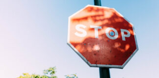 Spelinspektionen granskar informationskrav på licenshavarnas sajter Röd stoppskylt med texten STOP mot blå himmel och träd i bakgrunden.