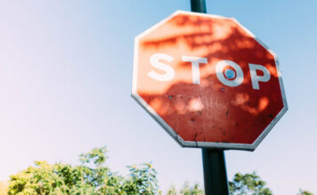 Spelinspektionen granskar informationskrav på licenshavarnas sajter Röd stoppskylt med texten STOP mot blå himmel och träd i bakgrunden.