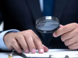 Person i kostym granskar dokument med förstoringsglas