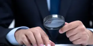 Så granskar Spelinspektionen nya aktörer på spelmarknaden Person i kostym granskar dokument med förstoringsglas