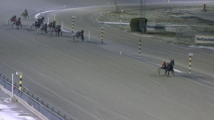 atg-står-inför-utmanande-år Travlopp på vintrig bana med ledande ekipage och flera hästar bakom under tävling på oval travbana.