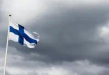 Gaming in Finland lanseras vid ICE 2026 Finlands flagga vajar i vinden mot en mörk och molnig himmel.