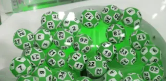 Gröna keno-bollar med svarta siffror samlade i genomskinlig behållare inför dragning.