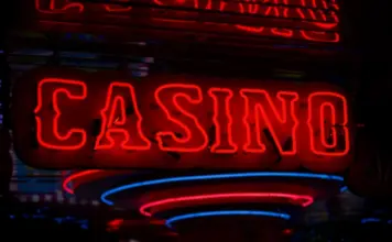 Röd neonskylt med texten ”CASINO” som lyser i mörker, symboliserar spelverksamhet och nattmiljö.