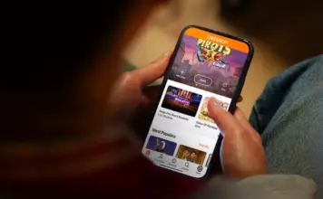 Person håller mobiltelefon med Betssons spelapp öppen