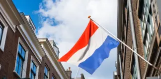 Polymarket förbjuds i Nederländerna – riskerar vite på 840 000 € Nederländernas flagga vajer mellan byggnader i stadsmiljö