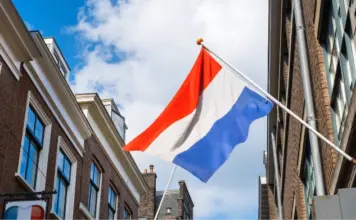 Polymarket förbjuds i Nederländerna – riskerar vite på 840 000 € Nederländernas flagga vajer mellan byggnader i stadsmiljö
