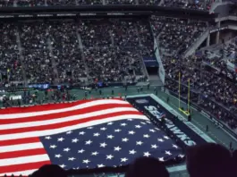 Amerikansk flagga täcker planen inför Super Bowl i fullsatt NFL-arena med publik på läktarna.