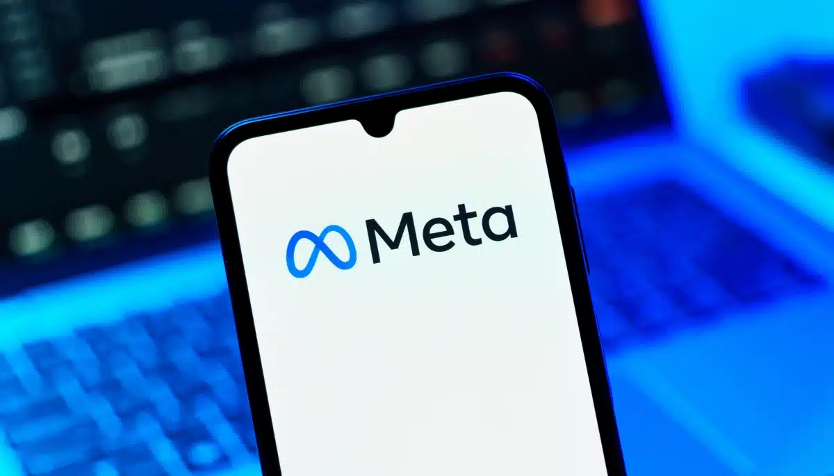Mobil med Meta logotyp framför suddig datorbakgrund