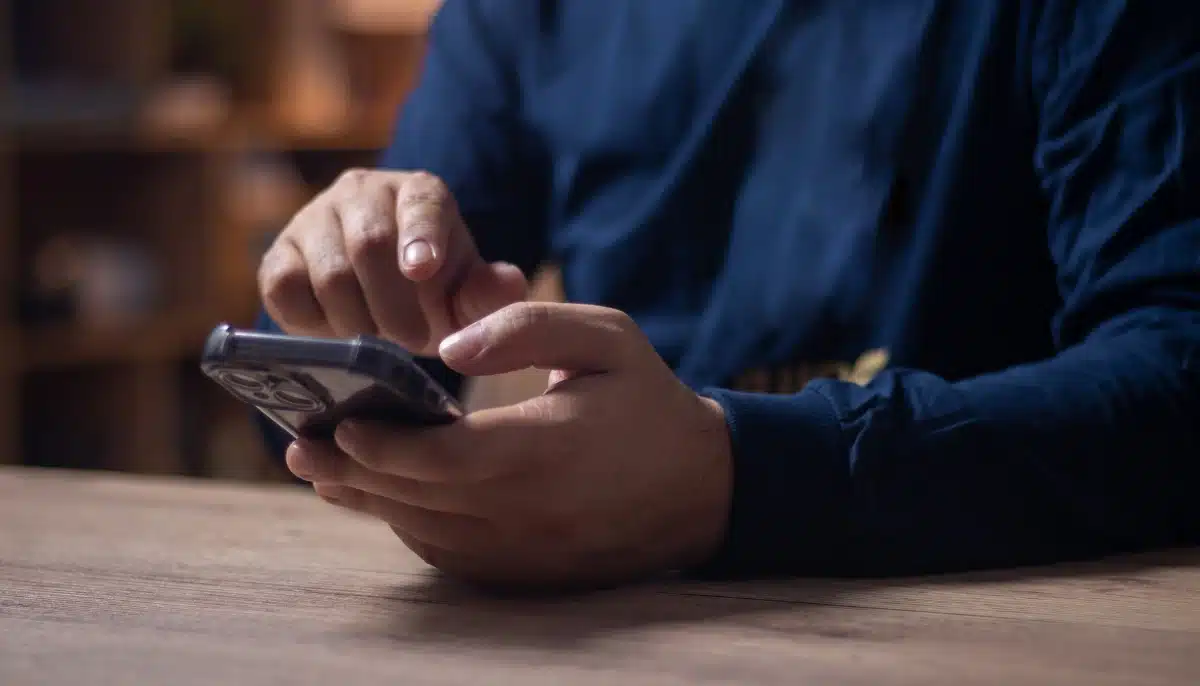 Person använder en mobiltelefon och kan ta emot SMS-reklam för olicensierat spel