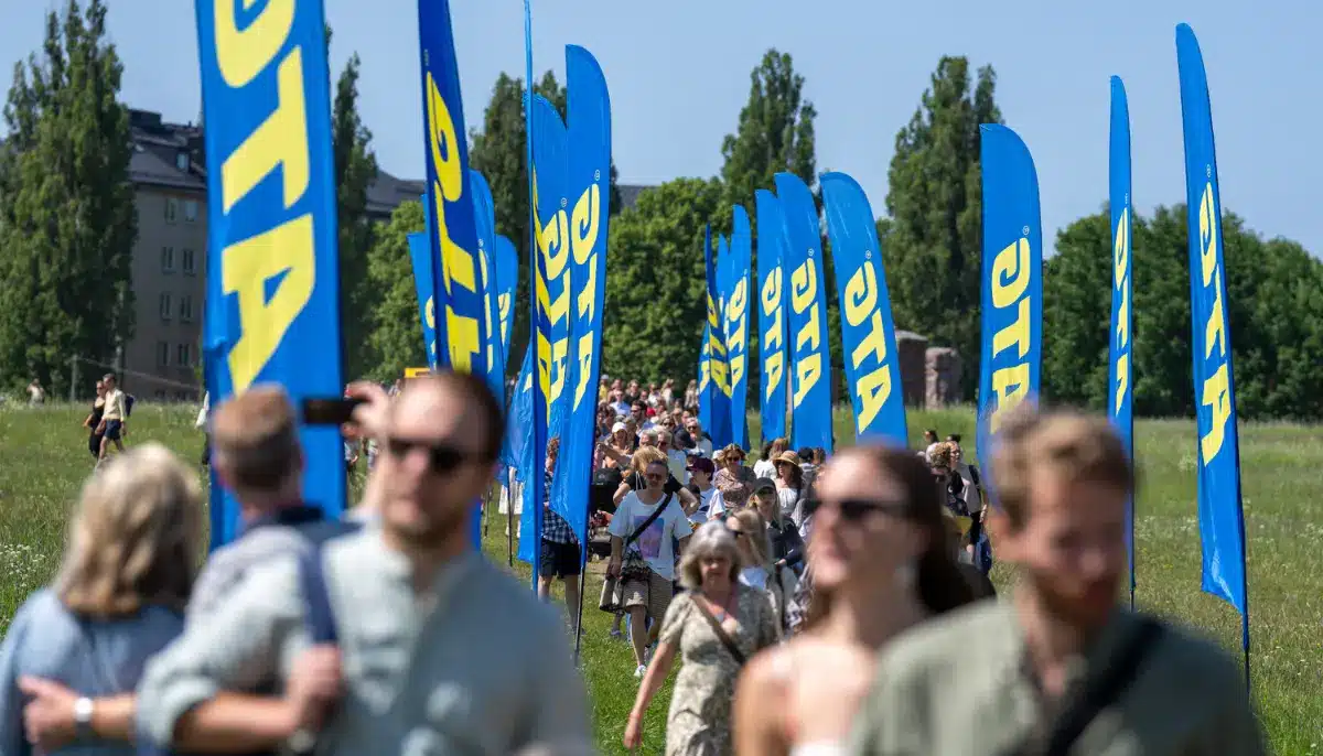Besökare går mellan blå ATG-flaggor vid ett utomhusevenemang